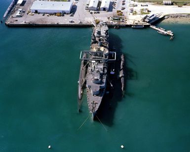 An overhead bow view of the submarine tender USS PROTEUS (AS 19) with two submarines moored alongside