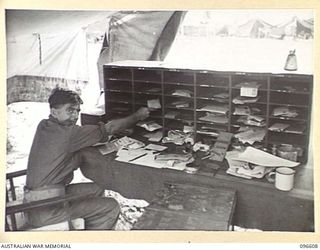 CAPE WOM, WEWAK AREA, NEW GUINEA. 1945-09-15. PRIVATE N. HEWARD SORTING MAIL IN THE POSTAL TENT, HEADQUARTERS 6 DIVISION