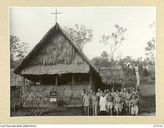 1943-06-25. NEW GUINEA. WORSHIPPERS LEAVING THE NEW ANGLICAN CHURCH OF THE RESURRECTION. WITH THEM IS PADRE. A.H. KIRK. (NEGATIVE BY N. BROWN)