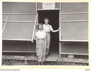 LAE, NEW GUINEA. 1945-11-08. SERGEANT J. CRAWFORD (1) AND LANCE CORPORAL E. HUMBERG (2) AUSTRALIAN WOMEN'S ARMY SERVICE INSTRUCTORS FOR THE COOKERY AND HOME CRAFT COURSE STANDING AT THE ENTRANCE TO ..