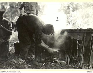 YAULA, NEW GUINEA. 1944-04-09. VX87461 PRIVATE J. CLARKE, 57/60TH INFANTRY BATTALION, PLACES SCENES IN AN OVEN ALONGSIDE THE BOGADJIM ROAD. THE OVEN HAS BEEN IMPROVISED FROM ABANDONED JAPANESE ..