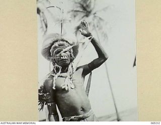 NEW GUINEA. 1942. A VILLAGE ELDER, RESPLENDENT IN HIS CEREMONIAL DRESS, WELCOMES PPI, MAJOR GENERAL B.M. MORRIS, DSO, COMMANDING OFFICER, NEW GUINEA LINES OF COMMUNICATION AREA AND THE AUSTRALIAN ..