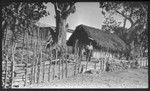 Man and child behind a fence, and near a house