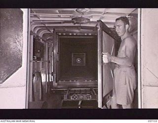 SEVENTEEN MILE, NEW GUINEA. 1943-09-23. NX47245 LANCE CORPORAL E. C. BELL OF THE 2/1ST AUSTRALIAN ARMY TOPOGRAPHICAL SURVEY COMPANY ADJUSTING AND FOCUSSING A SCREEN OF THE UNIT'S REPRODUCTION ..