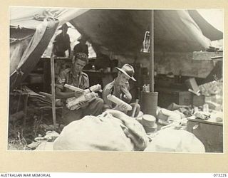 ALEXISHAFEN, NEW GUINEA. 1944-05. QX31923 PRIVATE B. EDWARDS (1), WITH NX69939 CORPORAL W.D. LINDSAY (2), SORTING MAIL FOR MEMBERS OF THE 2/15TH FIELD AMBULANCE. THE TENT IS PITCHED AT THE OLD ..