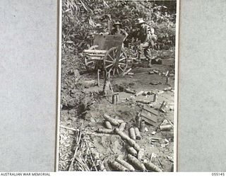 MUBO, NEW GUINEA, 1943-07-27. AN ABANDONED JAPANESE MOUNTAIN GUN AND AMMUNITION, RECOVERED BY THE AMERICANS FROM A DUGOUT AT KITCHENS CREEK. V504081 WARRANT OFFICER E. BRITTEN, AUSTRALIAN AND NEW ..