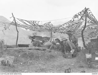 RAMU VALLEY, NEW GUINEA. 1943-10-23. A 25-POUNDER GUN OF "F" TROOP, 54TH BATTERY, 2/4TH AUSTRALIAN FIELD REGIMENT IN ACTION AGAINST JAPANESE POSITIONS. NOTE THE CAMOUFLAGE NET. SHOWN: VX16360 ..