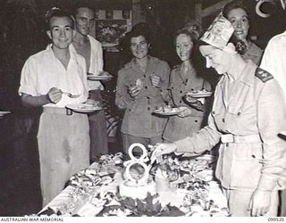 RABAUL, NEW BRITAIN, 1945-12-20. MATRON E. M. GREEN CUTTING THE CHRISTMAS CAKE AT A PARTY IN WARD 8, ATTENDED BY PATIENTS AND STAFF OF 118TH AUSTRALIAN GENERAL HOSPITAL