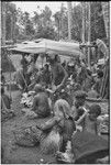 Mortuary ceremony, Omarakana: woman (center) carries basket of the deceased adorned with shell valuables and other items