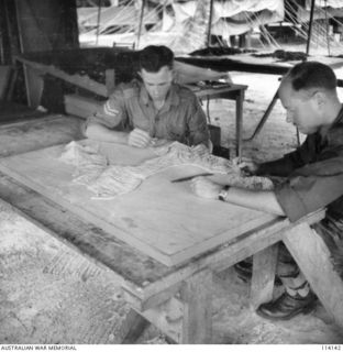 VX89654 Corporal Cyril John Berick (left), and Private S A Ashton, checking a plaster model of Rabaul, New Guinea, in the Modelling Section, Central Interpretation Unit, AIF