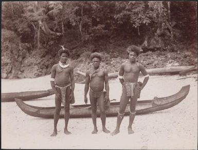 Three men standing next to canoes on a beach at Ahia, Ulawa, Solomon Islands, 1906 / J.W. Beattie