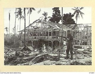 ALEXISHAFEN, NEW GUINEA. 1944-04-30. MEMBERS OF THE 30TH INFANTRY BATTALION AMONG THE BURNT REMAINS OF THE ROMAN CATHOLIC MISSION STATION. CORPORAL P. JOHNSON (1), HOLDS THE CROSS WHICH ONCE FORMED ..