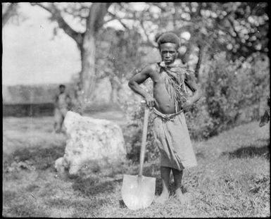 Man standing with a shovel beside a "sentinel" stone, Malaguna Road, Rabaul, New Guinea, 1936 / Sarah Chinnery