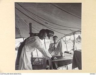 CAPE WOM, WEWAK AREA, NEW GUINEA. 1945-08-28. TROOPER P. DEVEREAUX, PATIENT AT 104 CASUALTY CLEARING STATION BEING PREPARED FOR X-RAY BY SERGEANT A. PINSON