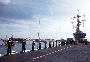 Sailors man the rails aboard the amphibious assault ship USS GUAM (LPH-9) as the vessel departs from port