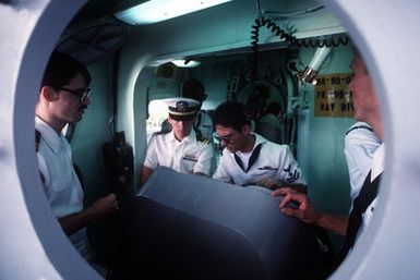 The helmsman mans the wheel of the battleship USS MISSOURI (BB-63) while other crew members stand by as the vessel prepares to depart from port at the beginning of Exercise RimPac '88