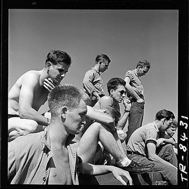 Enlisted men aboard USS Lexington (CV-16) during operations in the Gilbert and Marshall Islands. Crewmen gather around loud-speaker and listen intently as pilots relate story of attack on Japs at Kwajalein.