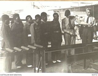 ALEXANDRIA, NSW. 1944-01-24. AUSTRALIAN AND NEW GUINEA ADMINISTRATION UNIT NATIVES BEING SHOWN WOODEN WATER CRAFT IN THE COURSE OF CONSTRUCTION AT SLAZENGER'S FACTORY