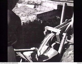 DONADABU, NEW GUINEA. 1943-11-09. WASTE SAWDUST RUNNING OFF A CONVEYOR BELT INTO A BARROW AT THE 9TH AUSTRALIAN WORKSHOP AND PARK COMPANY, ROYAL AUSTRALIAN ENGINEERS SAWMILL AT EILOGO. IT IS USED ..