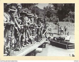MEVELO RIVER, HENRY REID BAY, NEW BRITAIN. 5 MARCH 1945. TROOPS OF C COMPANY, 14/32ND INFANTRY BATTALION WAITING ON A SECTION OF THE NEW BRIDGE UNDER CONSTRUCTION FOR THEIR TURN TO BE FERRIED ..