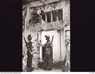 NAURU ISLAND. 1945-09-14. PRIVATE (PTE) J. STEPHENSON (1), AND PTE G. ALLEN, 31/51ST INFANTRY BATTALION, EXAMINING A JAPANESE SIGN ON A BOMB WRECKED BUILDING DURING A PATROL THROUGH THE TOWN AREA