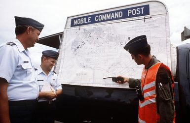 Fifteen Air Base Wing officers, participating in a space shuttle emergency landing exercise, examine a map of the exercise area attached to the US Air Force Disaster Response Force mobile command post. They are, left to right: Colonel Fred Lugis, Lieutenant Colonel Willian H. Follmer, and COL Ronold J. Tribo, on-the-scene commander for the exercise