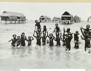 NEW GUINEA. 1942. NATIVE CHILDREN FROLICING IN THE SEA AT ONE OF THE VILLAGES VISITED BY PPI. MAJOR GENERAL B.M. MORRIS, DSO, COMMANDING OFFICER, NEW GUINEA LINES OF COMMUNICATION AREA AND THE ..