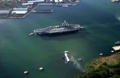 Aerial view of the US Navy (USN) Aircraft Carrier USS NIMITZ (CVN 68) passing by the battleship USS Arizona (BB 39) Memorial as sailors spell out FREEDOM on the flight deck and man the rails prior to pulling in for liberty. This is the first port call for the ship following her transit around South America. The NIMITZ is en route to her new homeport at San Diego, California (CA)