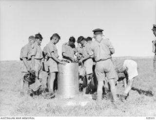 FORBES, AUSTRALIA. 1943-02. "GUINEA PIGS" TAKING PART IN A GAS SHELL EXPERIMENT DEPOSITING CONTAMINATED CLOTHING IN THE APPROPRIATE BINS TO BE TAKEN TO THE DECONTAMINATION POINT