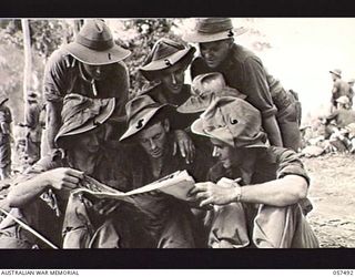 NADZAB, NEW GUINEA. 1943-09-20. TROOPS OF "B" COMPANY, 2/16TH BATTALION, 21ST AUSTRALIAN INFANTRY BRIGADE, ENJOYING A MAGAZINE WHILE WAITING FOR AN AIRCRAFT TO TAKE THEM TO KAIAPIT. LEFT TO RIGHT: ..