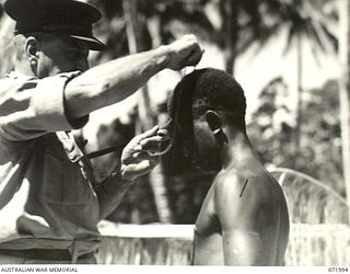 LAE, NEW GUINEA. 1944-04-01. LOIS (1), A NATIVE CARRIER WITH THE AUSTRALIAN NEW GUINEA ADMINISTRATIVE UNIT, BEING PRESENTED WITH THE LOYAL SERVICE MEDAL FOR BRAVERY AT BUNA BY MAJOR GENERAL B.M. ..