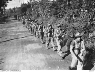 RABAUL, NEW BRITAIN, 1945-09-11. TROOPS OF 22 INFANTRY BATTALION MOVING THROUGH RABAUL ON A PATROL ACROSS TUNNEL HILL ROAD TO SECURE THE AREA. THE TROOPS FORMED PART OF THE FORCE DRAWN FROM 4 ..