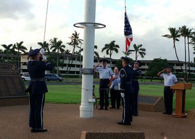 US Air Force Colonel (COL) Bruce Brown, Commander of the 15th Air Base Wing, Hickam AFB, Hawaii, Mr. Robert May a survivor of the attack on Pearl Harbor and USAF Major (MAJ) Joseph E. Davis salute as members of the 15th Air Base Wing Honor Guard raise the Flag during a twilight ceremony held at Hickam Air Force Base