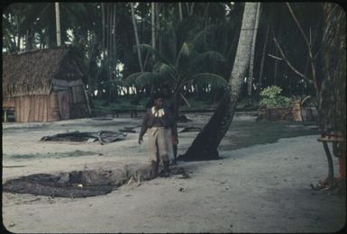 A village woman and man standing next to a hole for burying coconuts : Tasman Islands, Papua New Guinea, 1960 / Terence and Margaret Spencer