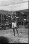 Meeting: man speaks in front of gathered crowd, his arm raised