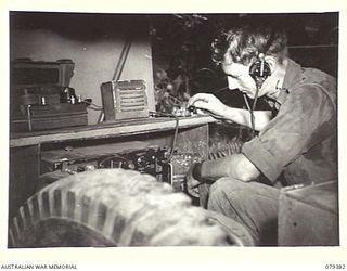 LAE, NEW GUINEA. 1945-03-11. VX86703 SIGNALLER G. MITCHELL, 34TH WIRELESS SECTION (HEAVY) 19TH LINES OF COMMUNICATION SIGNALS WORKING THE KEY OF A WS133 TRANSMITTER. ALSO SEEN IS A MOBILE RECEPTION ..