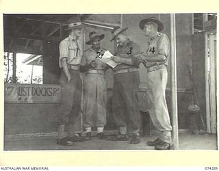 MADANG, NEW GUINEA. 1944-06-26. OFFICERS OF THE 7TH DOCKS OPERATING COMPANY, CHECKING BILLS OF LADING ON THE VERANDAH OF THEIR OFFICE. IDENTIFIED PERSONNEL ARE:- VX47786 CAPTAIN R.P. BRYANT (1); ..