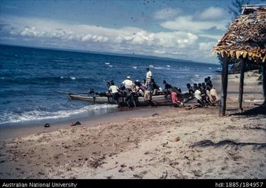 Men pushing canoe out to sea