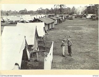 LAE, NEW GUINEA. 1944-03-24. VX43600 LIEUTENANT S. PENGELLY (1), WITH NX27041 WARRANT OFFICER CLASS 2 R. THOMPSON (2), IN THE AREA OF WORKSHOPS AND ADMINISTRATION BUILDINGS AT THE 2/125TH BRIGADE ..