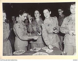 TOROKINA, BOUGAINVILLE. 1945-07-02. MATRON M.E. HURLEY (2) AND SOME OF THE AUSTRALIAN ARMY NURSING SERVICE SISTERS HAVING A SHERRY IN THE MESS ANTE-ROOM AT THE SISTERS' MESS, 2/1 GENERAL HOSPITAL. ..