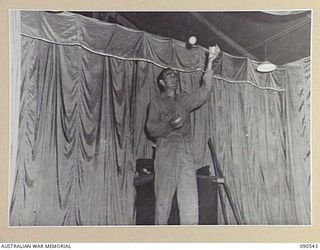 JACQUINOT BAY, NEW BRITAIN. 1945-04-15. PRIVATE W. KALIS, PERFORMS A JUGGLING ACT ON THE SMALL STAGE DURING A CONCERT STAGED BY MEMBERS OF 33 DOCKS OPERATING COMPANY, ROYAL AUSTRALIAN ENGINEERS