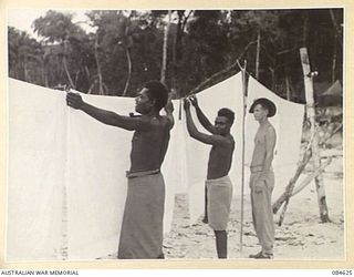 GREEN ISLAND, BOUGAINVILLE AREA, SOLOMON ISLANDS. 1944-12-19. PRIVATE A E HUTCHINSON, HQ 17 FIELD AMBULANCE, (3), WATCH NATIVE HELPERS BULLANESE, (2), AND NO. 1 BOY BONGA, (3), HANG FRESHLY WASHED ..