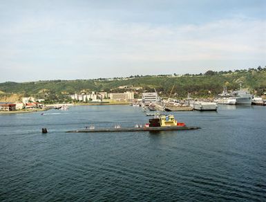 Aerial starboard view of the Los Angeles-class Attack Submarine, USS TOPEKA (SSN 754) as a tugboat tows the sub toward its berth at the Naval Submarine Base, California. The TOPEKA homeport is Pearl Harbor, Hawaii