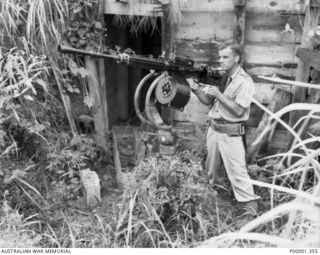 NEW BRITAIN, 1945-09. A NEW ZEALAND AIR FORCE OFFICER INSPECTING A JAPANESE SINGLE BARRELLED QUICK FIRING ANTI-AIRCRAFT GUN IN THE RABAUL AREA. (RNZAF OFFICIAL PHOTOGRAPH.)