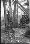 House-building for Rappaports: men smoke, taking a break from sharpening support posts with machetes