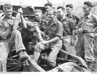 DUMPU, RAMU VALLEY, NEW GUINEA. 1943-12-25. PERSONNEL OF "C" TROOP, NO. 8 BATTERY, 2/4TH FIELD REGIMENT WRITING MERRY CHRISTMAS ON 25 POUNDER SHELLS WHICH THEY WILL FIRE INTO JAPANESE POSITIONS AS ..