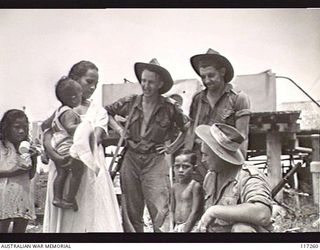 NAURU ISLAND. 1945-09-14. PRIVATE (PTE) JOPLING (1), PTE S. DART (2) AND PTE A. SPLETTER (3) OF THE 222ND AUSTRALIAN SUPPLY DEPOT PLATOON CHATTING WITH A NAURUAN WOMAN WHILE OUT ON A PATROL