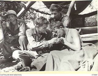 1943-08-10. NEW GUINEA. MOUNT TAMBU FIGHTING. PTE. ROY STURNER, OF REDFERN, N.S.W. WHO WAS WOUNDED IN THE FIGHTING ON MOUNT TAMBU CHATS WITH SGT. HARRY HILL, OF ROSEBERG, OREGON, AND 1ST CLASS PTE. ..