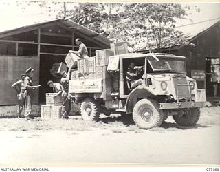 NEW GUINEA. 1944-12-14. PERSONNEL UNLOADING CASES OF AUSTRALIAN COMFORTS FUND GOODS FROM A TRUCK INTO THE UNIT STORE UNDER THE SUPERVISION OF MAJOR HEARN, DIRECTOR