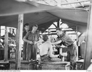 ALEXISHAFEN, NEW GUINEA. 1944-04-30. THE REGIMENTAL AID POST AT HEADQUARTERS 30TH INFANTRY BATTALION WHICH HAS BEEN ESTABLISHED IN THE REMAINS OF THE LIVING QUARTERS AT THE ROMAN CATHOLIC MISSION. ..